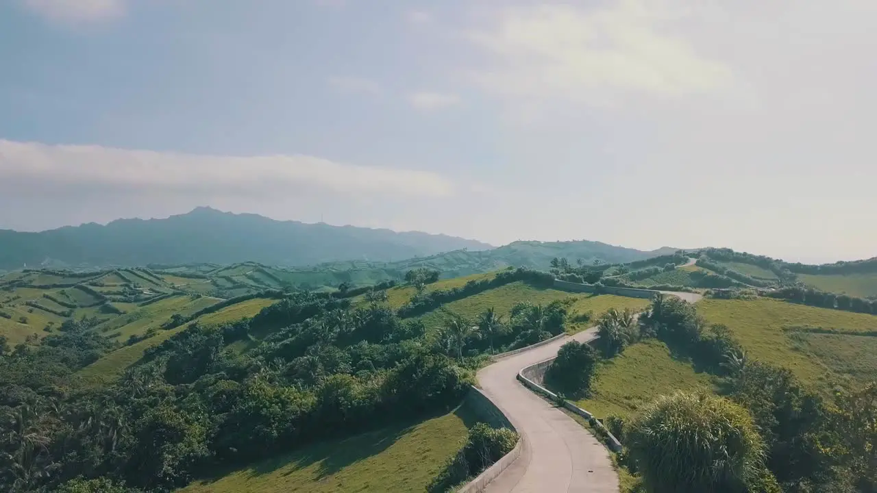 Cinematic aerial drone video of a roadline into a picturesque mountain view of Batanes in the Philippines