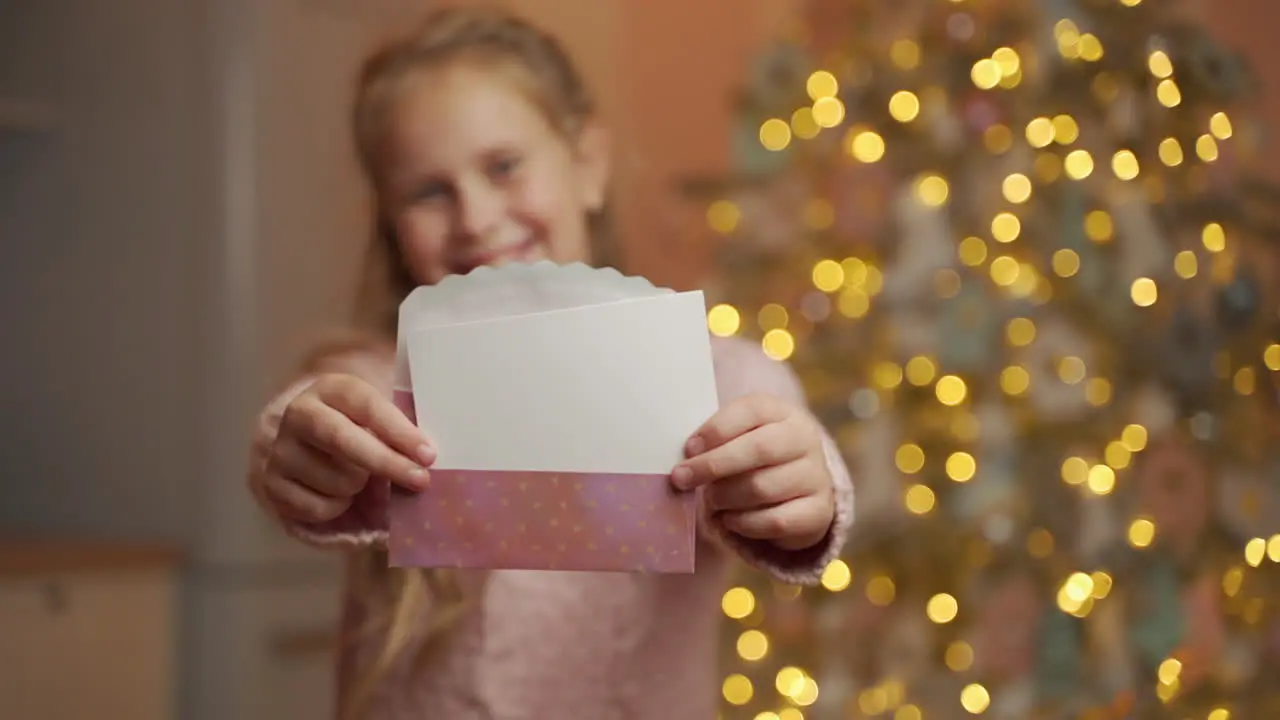 Girl Holding White Christmas Card With Blank Space Showing It To Camera