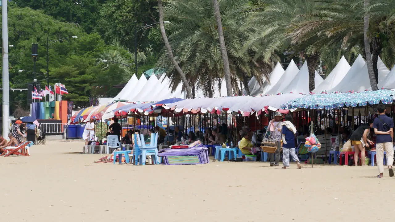 Vendors People enjoying the beach beach chairs umbrellas and canopies busy beach scenario in Pattaya Thailand