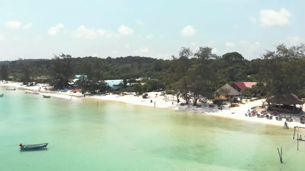 Paradisiac clear water full of fishing boats bathing the golden sand at Sok San Beach in Koh Rong Sanloem Cambodia Aerial Fly-over shot