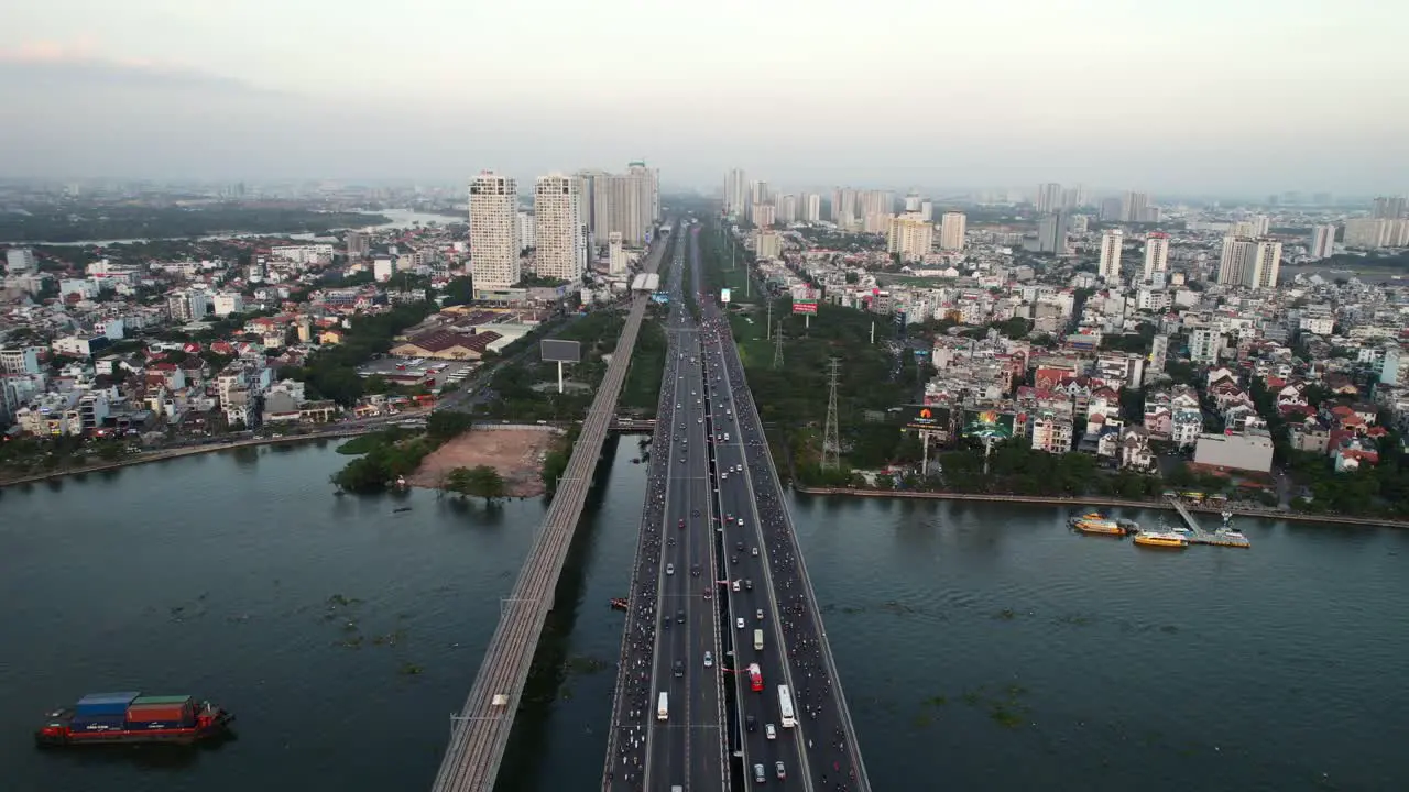 aerial of cars and motorbikes driving over a bridge on a long highway road in Ho Chi Minh City Vietnam at sunset