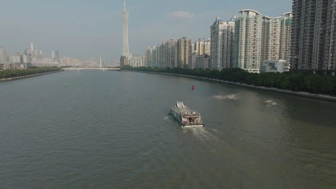 Aerial follow shot of a ferry boat on the river in downtown Guangzhou city China