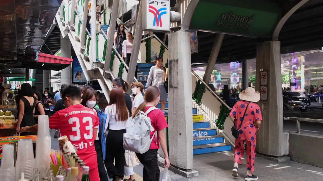 Camera pans to the left revealing the BTS Phrom Phong Station vendors on the left and people going up and down the stairs Sukhumvit Bangkok Thailand