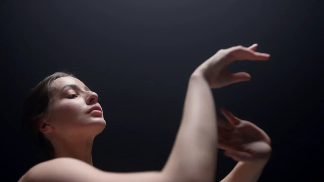 Ballet dancer practicing in dark background Ballerina moving hands indoors