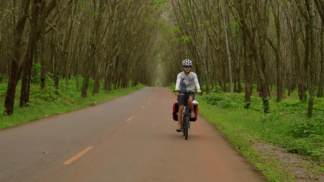 Frontal view woman cyclist in tropical southeast asia jungle bikepacking