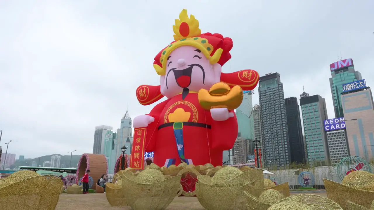 A man walks across the frame in front of a Chinese New Year theme installation event for the Chinese Lunar New Year as skyscrapers are seen in the background in Hong Kong