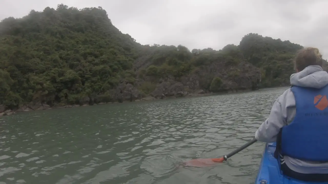 a woman in a kayak paddling seen from the back