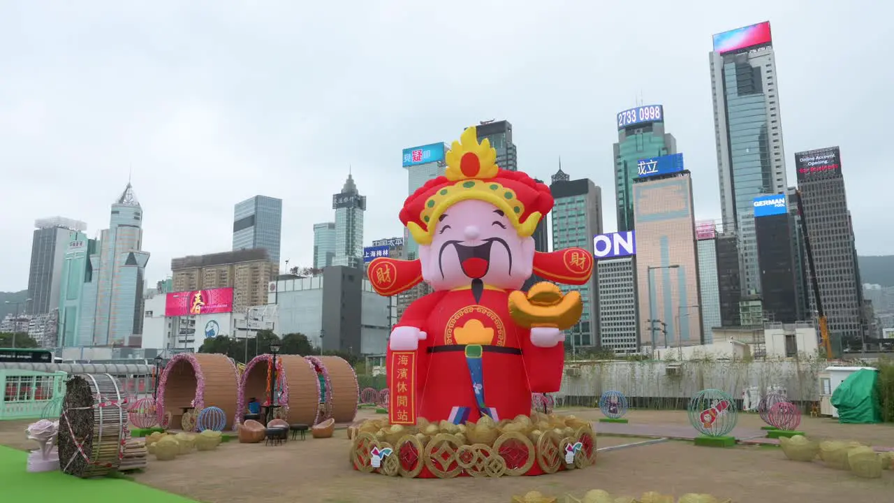 A woman takes photos of an outdoor Chinese New Year theme installation event for the Chinese Lunar New Year as skyscrapers are seen in the background in Hong Kong