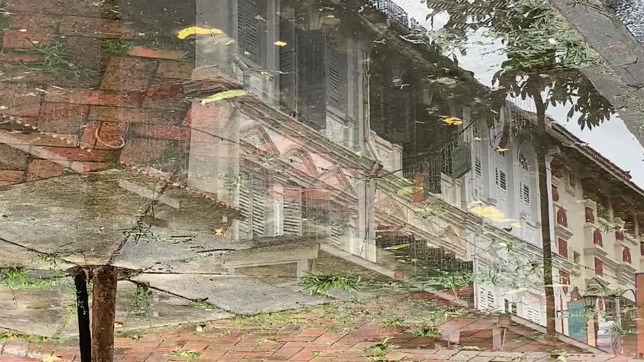 Reflection in the water of shophouses in Singapore with people walking by in the daylight