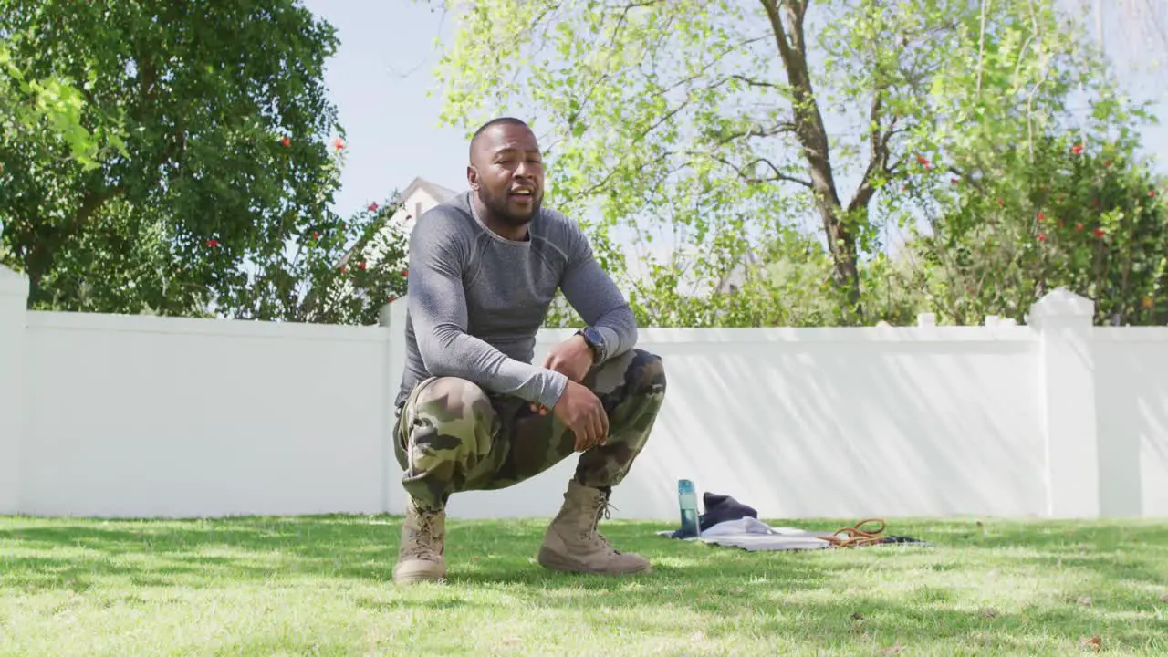 Tired african american male soldier exercising in a sunny garden