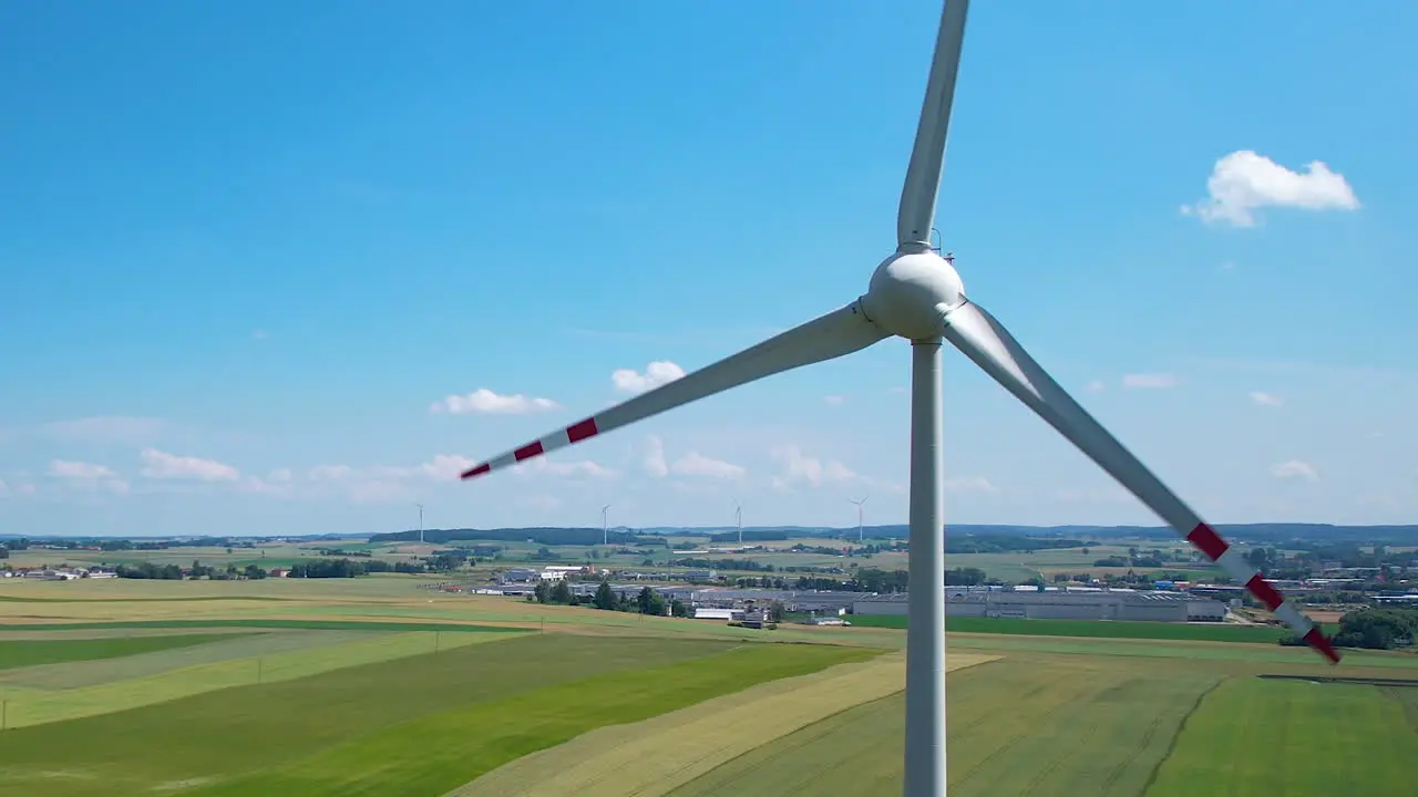 Rotating wind turbine agains blue sky in green farm landscape aerial