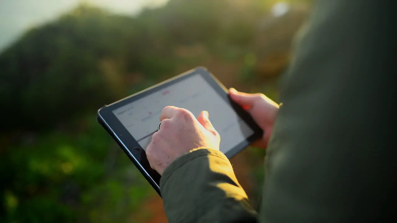 an unrecognizable man using a tablet outdoors