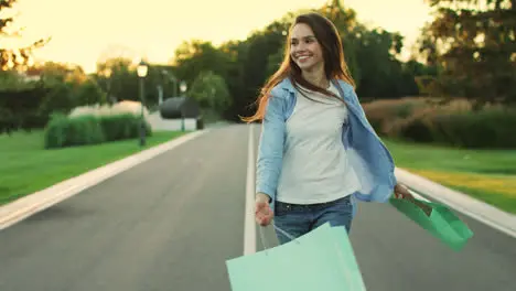 Happy woman with purchase in bag walking in city park Happy girl