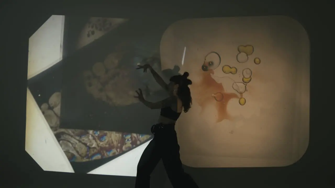 Woman narrates a story through dance and gestures while others change the scenery creating incredible effects with a projector