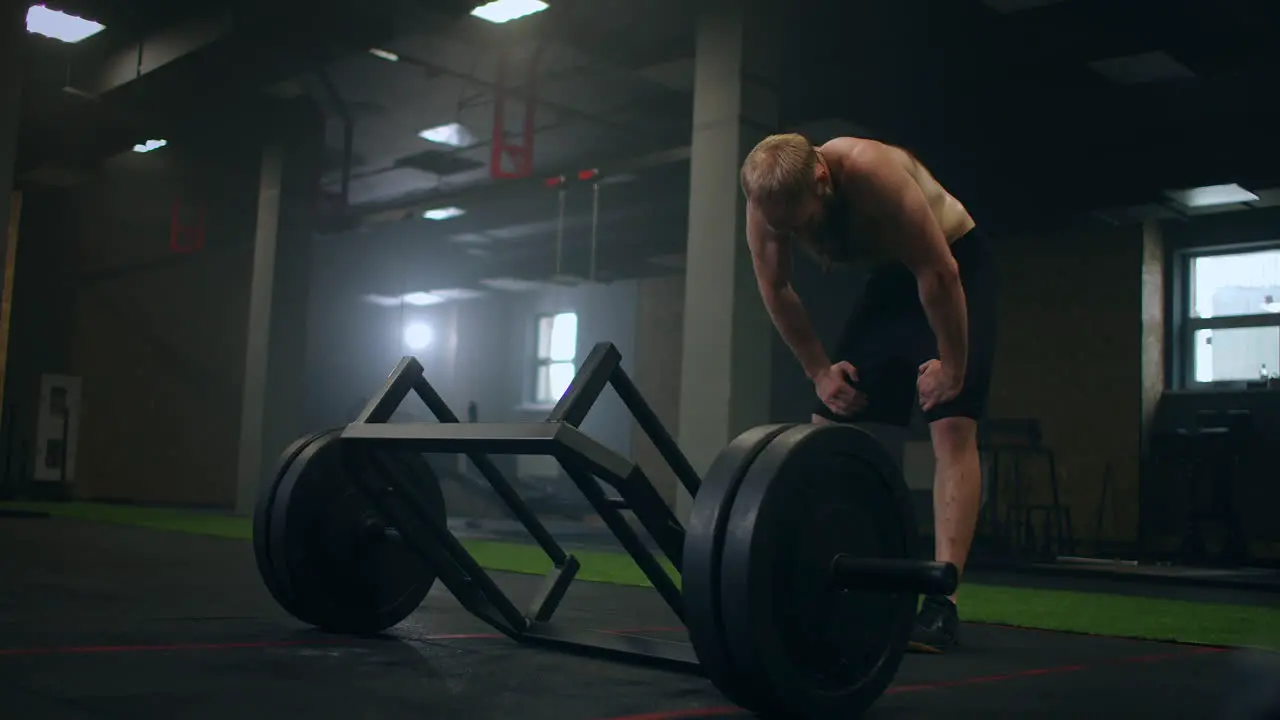 A tired man rests After lifting weights vilnay exercise deadlifts Preparing and adjusting concentration before training Mood and heavy breathing of an athlete with vapor in the gym