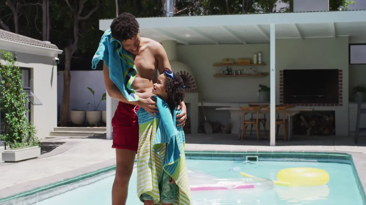 Happy biracial man and his son standing by swimming pool in garden