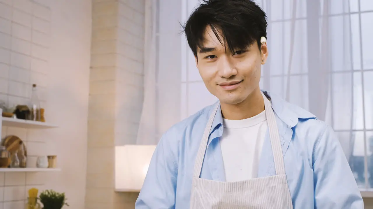 Japanese Man Cutting Ingredients In The Kitchen Then Looks At The Camera And Smiles