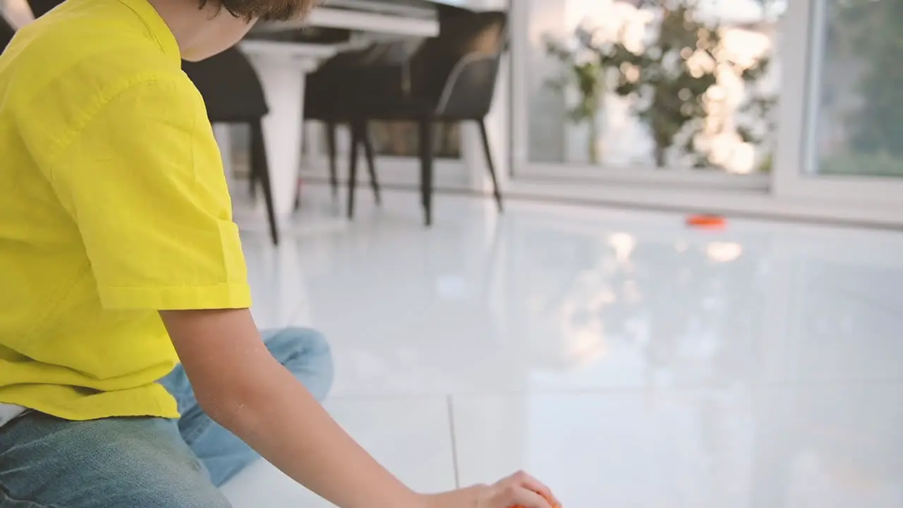 Blond Boy With Curly Hair Sitting On The Floor Playing With His Dog And A Ball