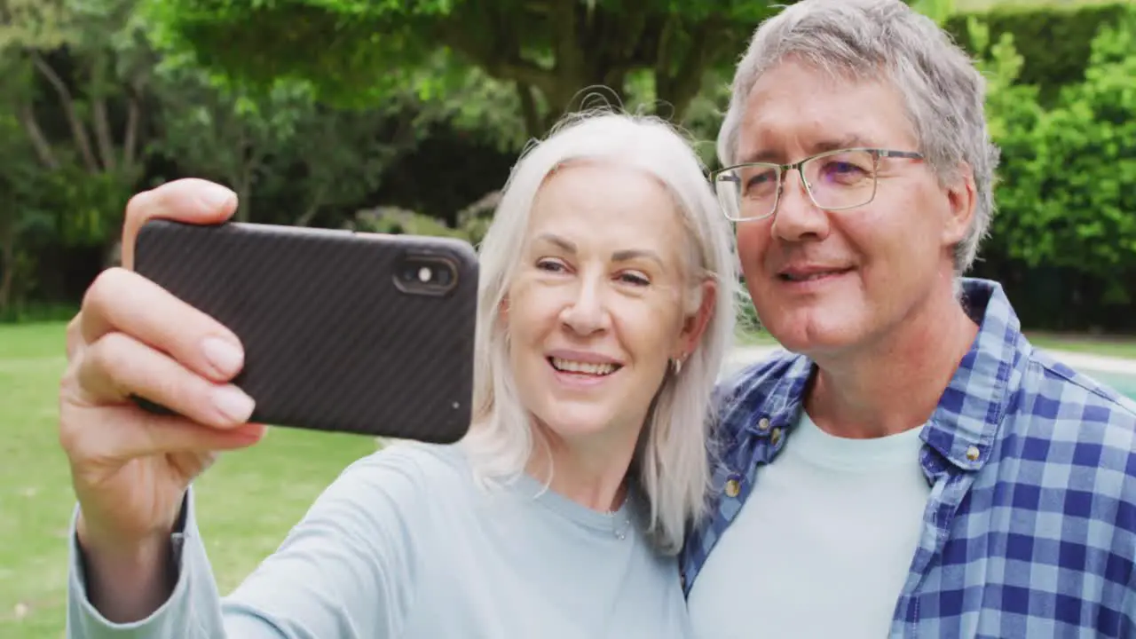 Animation of caucasian senior couple embracing in garden taking selfie