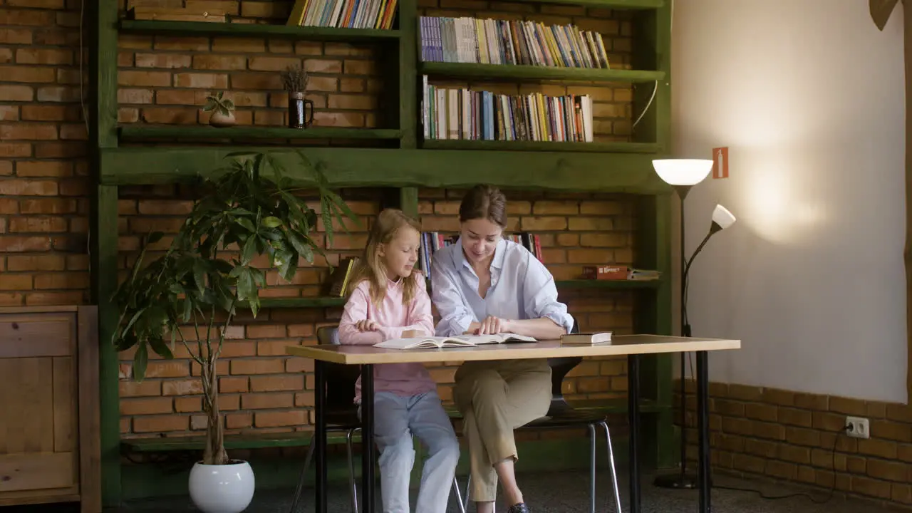 Young teacher and blond student reading the Bible together