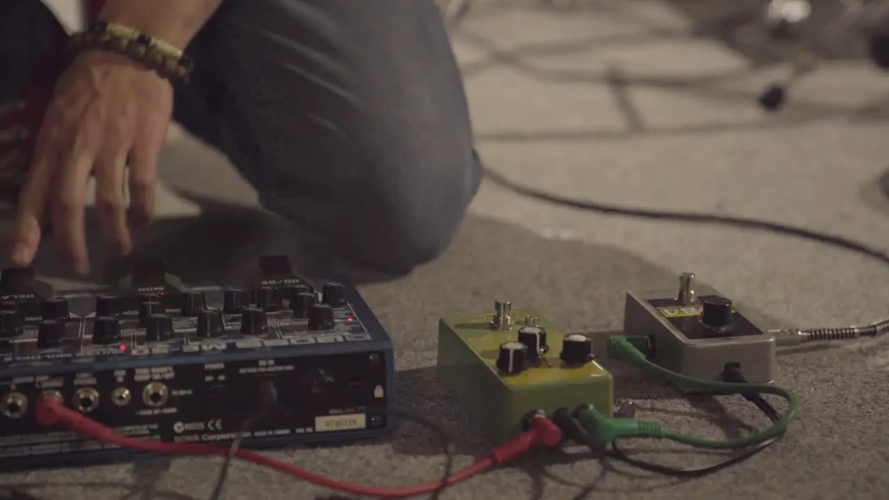 Person setting up sound board electric guitar effects pedals before concert