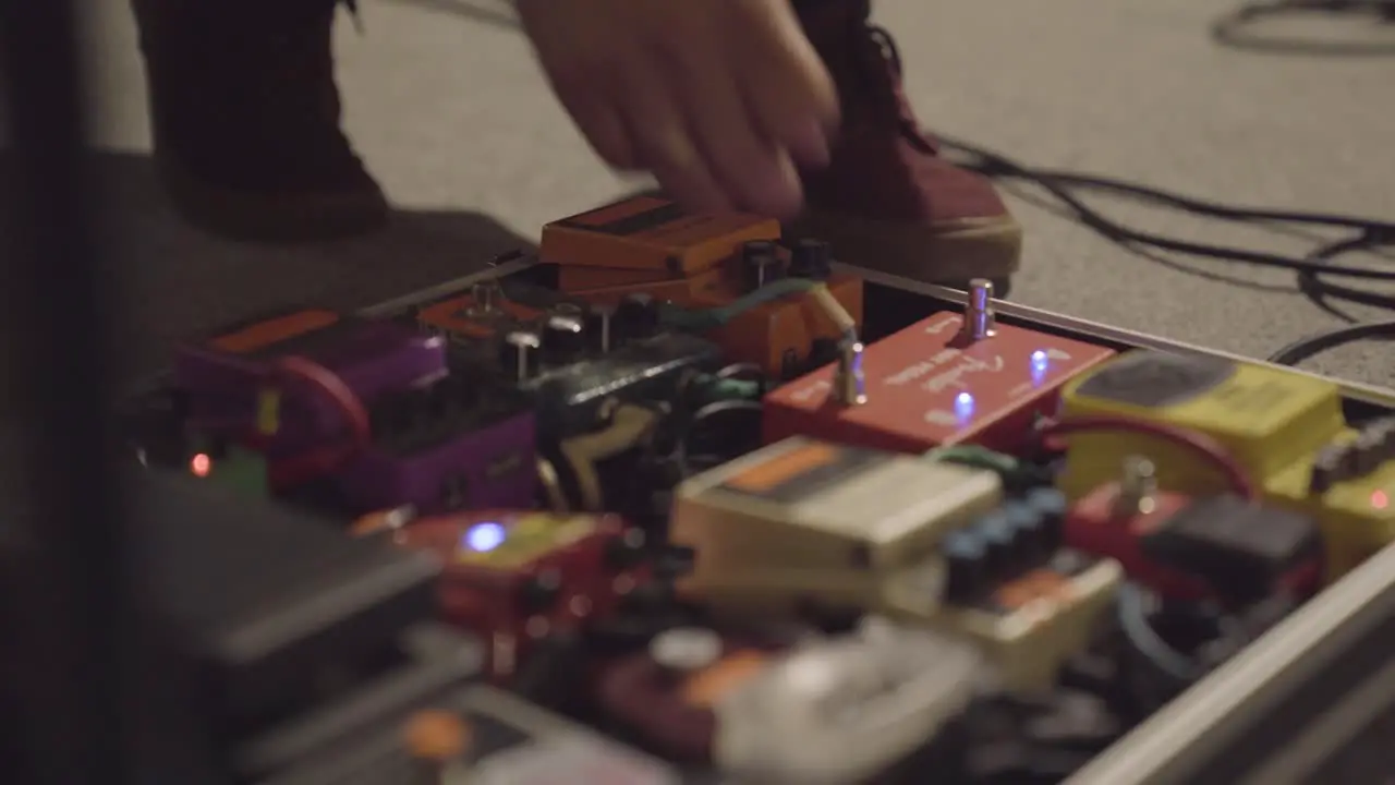 Person checking pedals switches for electric guitars during concert setup