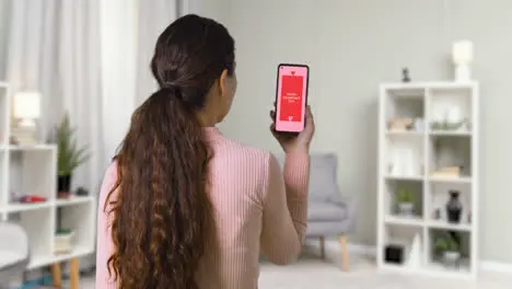 Woman At Home Looking At Happy Valentine's Day Message On Mobile Phone