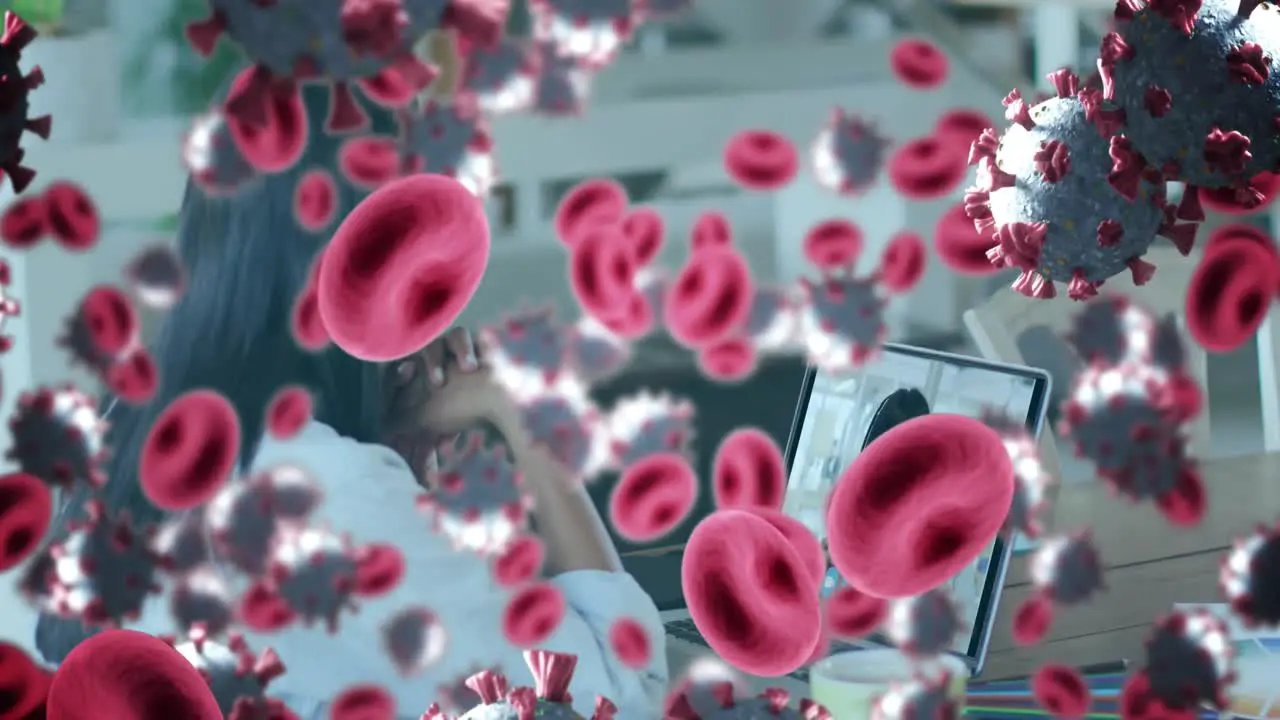 Animation of covid 19 cells and red blood cells over businesswoman using laptop