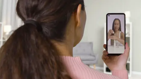 Close Up Of Woman At Home Looking At Beauty Product Demonstration Video On Mobile Phone