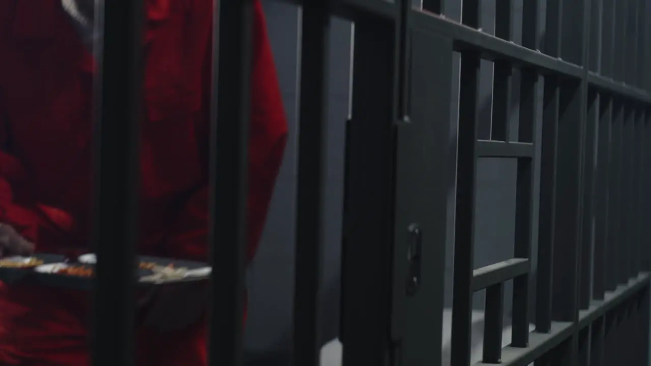 Close Up of Prisoner in Orange Uniform Holding Metal Bars in Prison Cell     (Stock Footage)