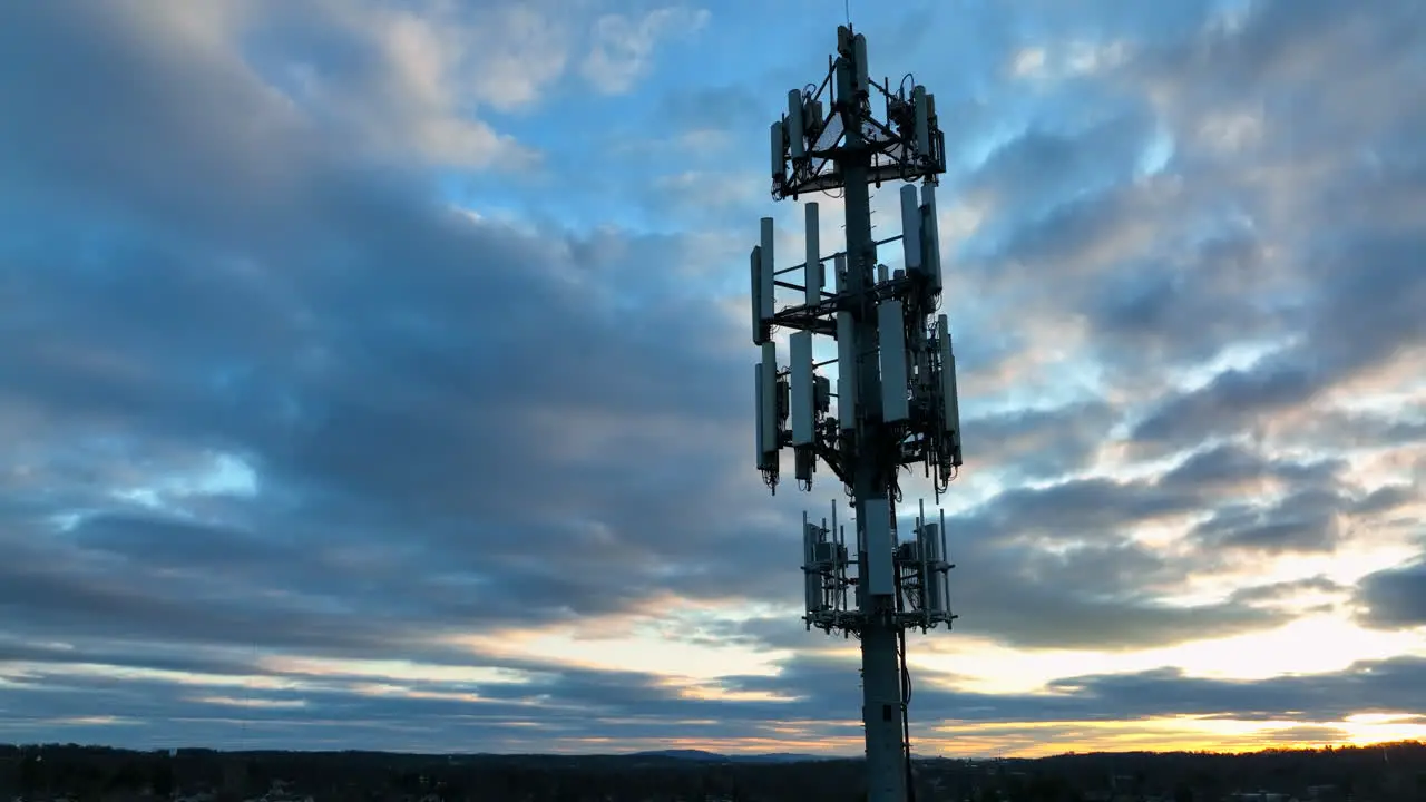 Aerial of cell phone tower at night against sunset sky in American town