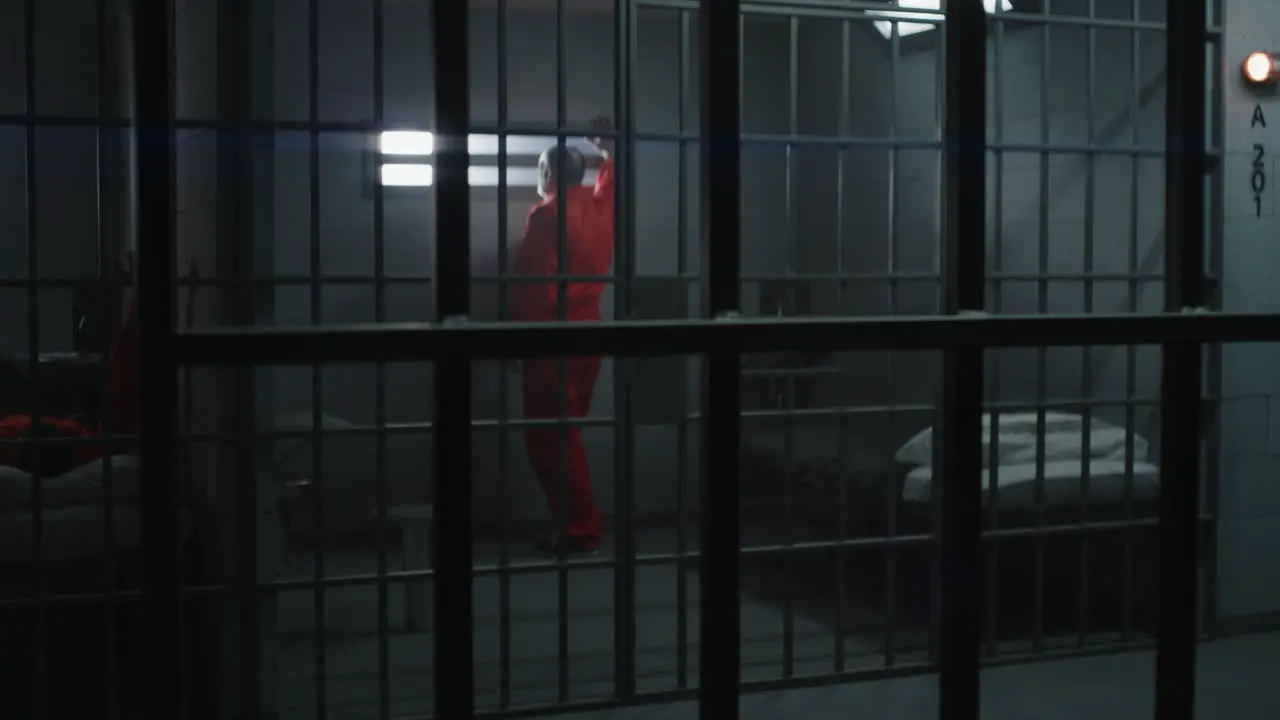 Elderly Prisoner Leans on Metal Bars and Looks at Camera