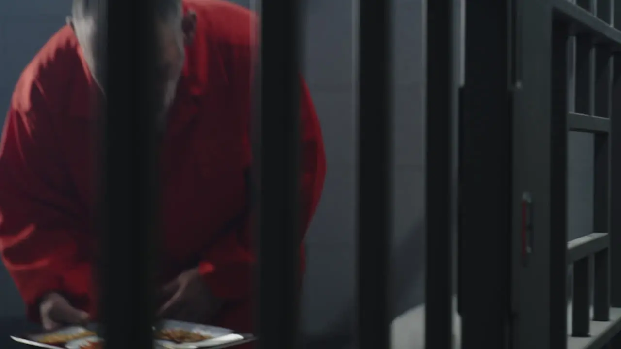 Prison Guard Gives Food to Prisoner Through Metal Bars