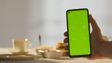 Person Holding Green Screen Mobile Phone With Traditional British Afternoon Tea With Scones Cream And Jam In Background