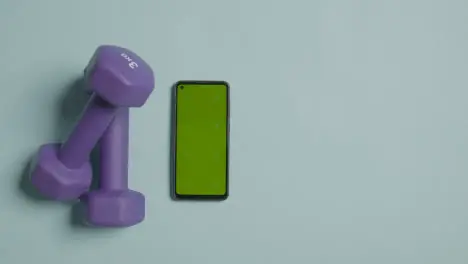 Overhead Fitness Studio Shot Of Male Hand Picking Up Exercise Dumbbell Weights Next To Green Screen Mobile Phone 4