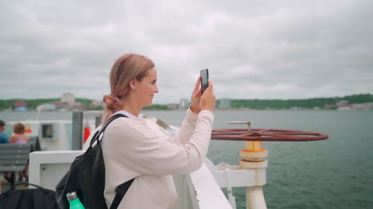 Woman with pink hair on the coast of eastern Canada taking a phone on her cell phone during midday