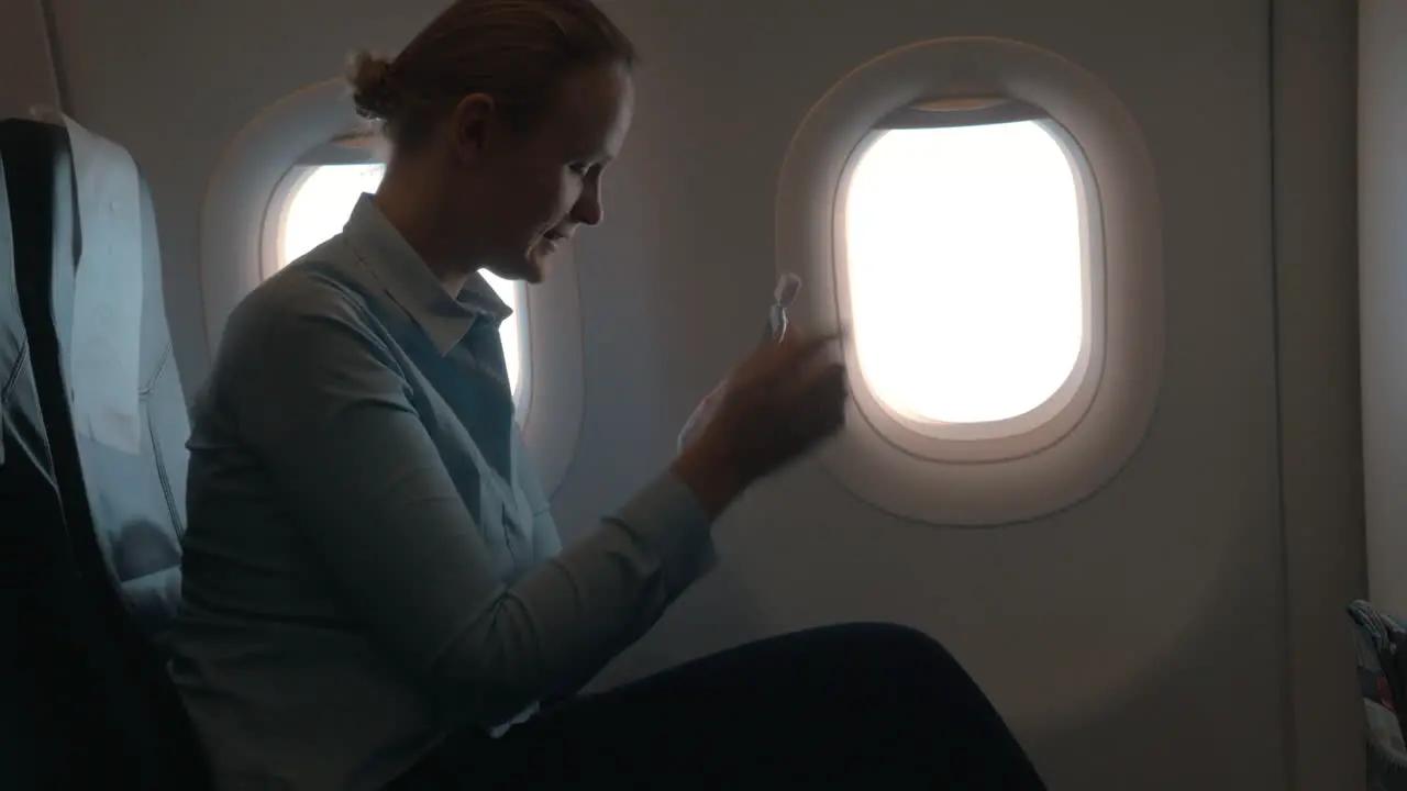 In cabin of plane girl sitting on chair and using mobile terminal on phone and pays for purchase through card