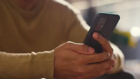 Close Up Of Muslim Man At Home Holding Mobile Phone And Scrolling