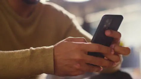 Close Up Of Muslim Man At Home Holding Mobile Phone And Scrolling 1