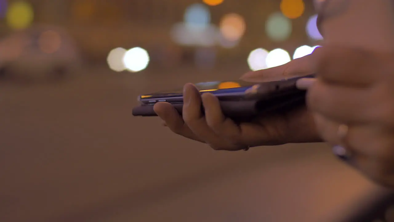 Young girl in evening street connects to the mobile phone portable charger