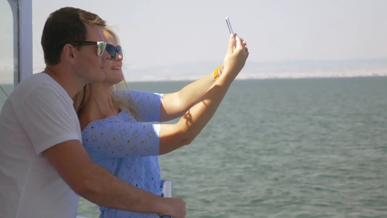 On sea in city of Perea Greece on a ship young couple doing selfie on a mobile phone