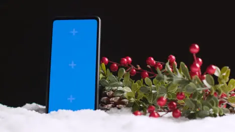 Blue Screen Mobile Phone On Christmas Background With Snow And Foliage 3