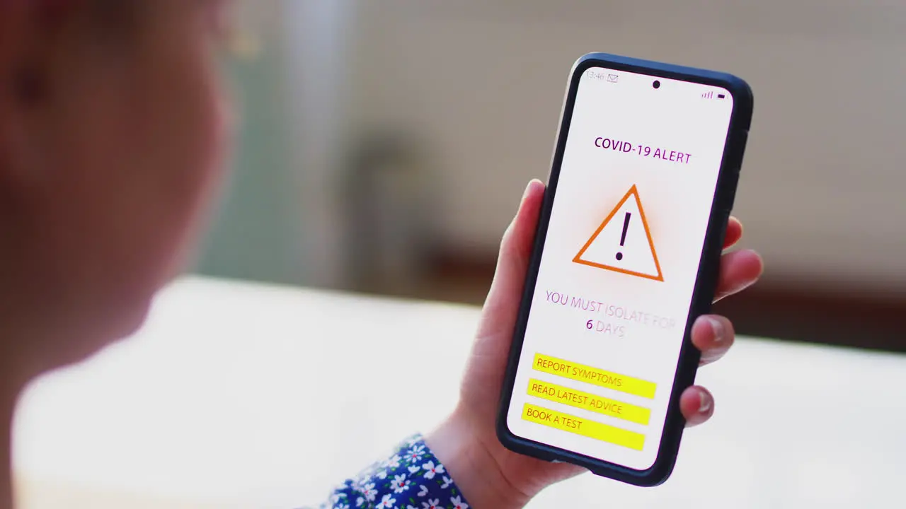 Close up of woman holding mobile with Covid 19 Track and Trace alert on screen shot in slow motion