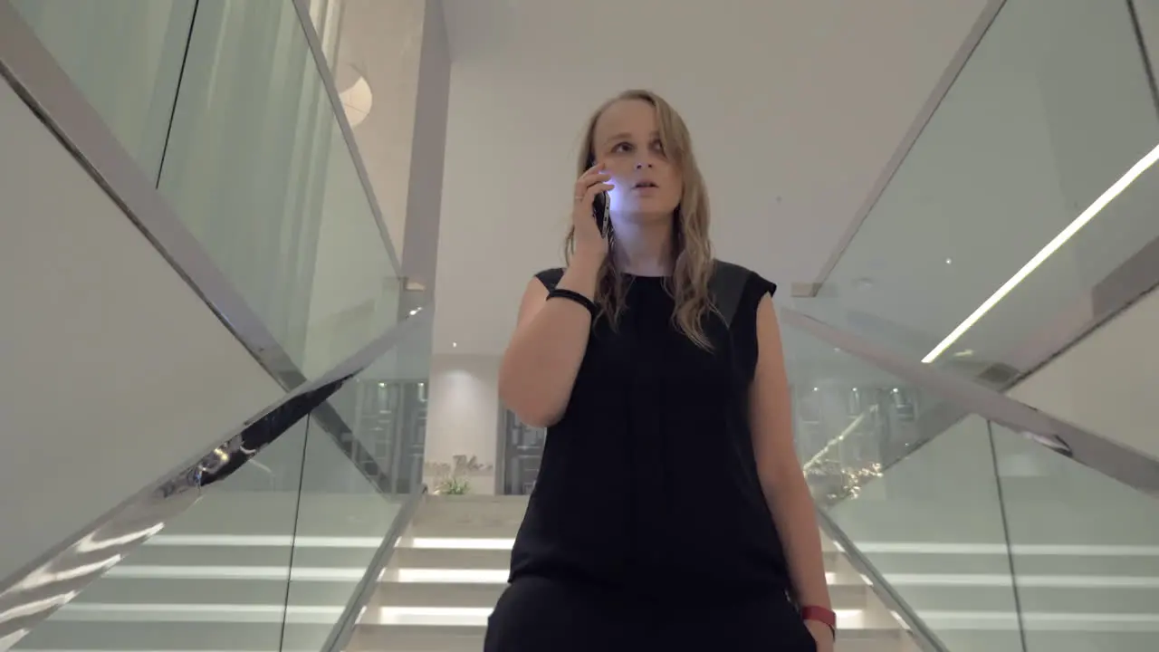 A young woman talking to a smartphone while going downstairs