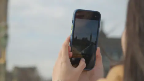 Close Up Of Woman On Holiday Taking Photo Of Houses Of Parliament In London UK On Mobile Phone