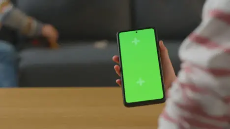 Close Up Of Boy Playing With Toy Dinosaurs As Girl Uses Screen Mobile Phone