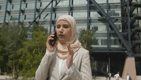 Muslim Businesswoman On Mobile Phone Standing Outside Office In City 3