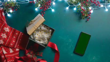 Overhead Shot Of Green Screen Mobile Phone With Christmas Decorations Holly Berries And Presents