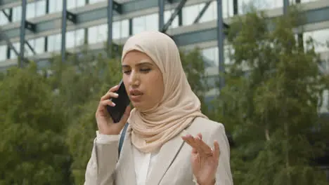 Muslim Businesswoman On Mobile Phone Standing Outside Office In City 2