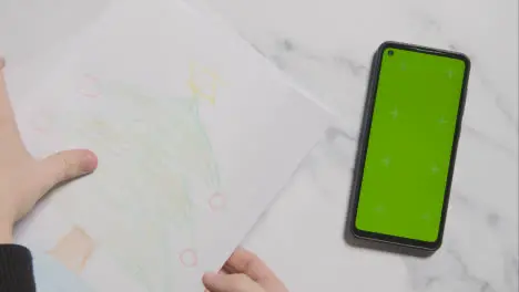 Overhead Shot Of Child With Coloured Pencils And Drawing And Green Screen Phone On Marble Background